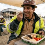 Trabajador alimentándose de forma equilibrada con un almuerzo rico en proteínas durante su jornada laboral.
