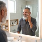 Botella de limpiador facial masculino sobre lavabo, primer paso de la rutina de cuidado facial para hombres.