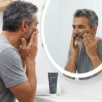 Caballero maduro aplicando exfoliante facial para limpiar las células muertas de su rostro.