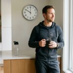 Hombre atlético sosteniendo una taza de café negro en una cocina moderna por la mañana, ilustrando el protocolo de ayuno intermitente para hombres.