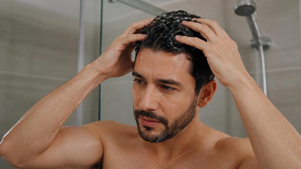 Hombre aplicando correctamente champú anticaspa sobre el cuero cabelludo